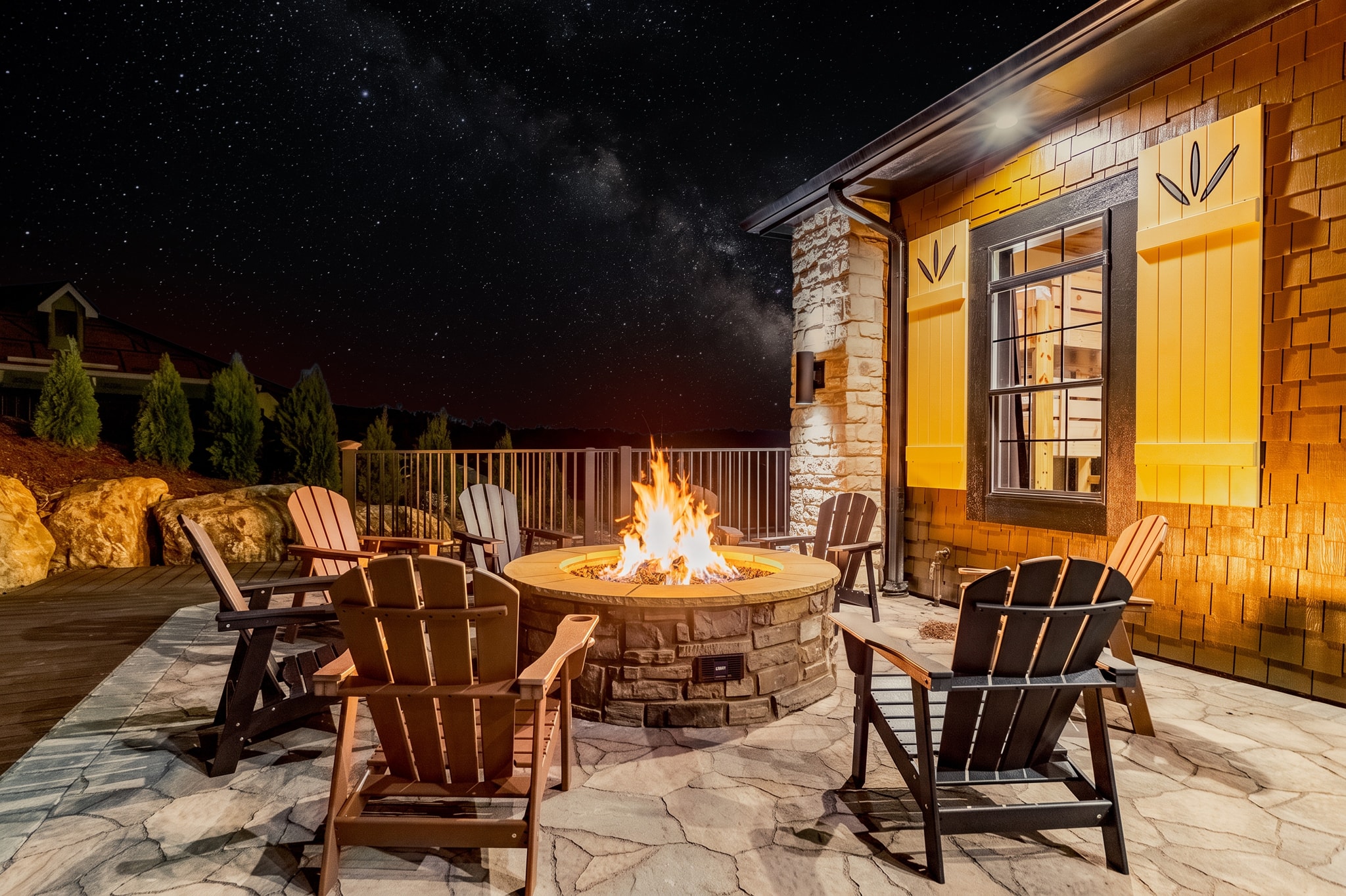 Excalibur fire pit at night under the Milky Way starry sky with Adirondack chairs and lodge exterior