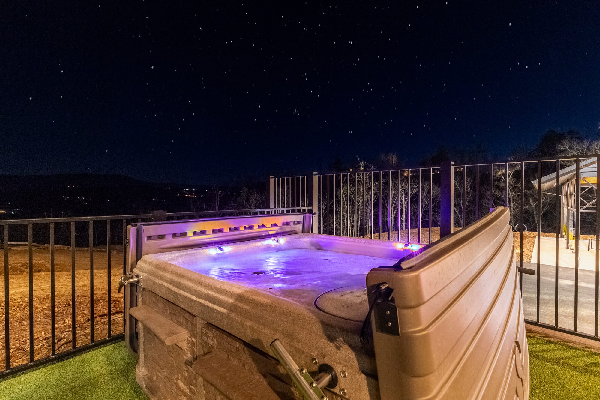 Excalibur outdoor hot tub with purple LED lighting under starry sky, mountain valley views
