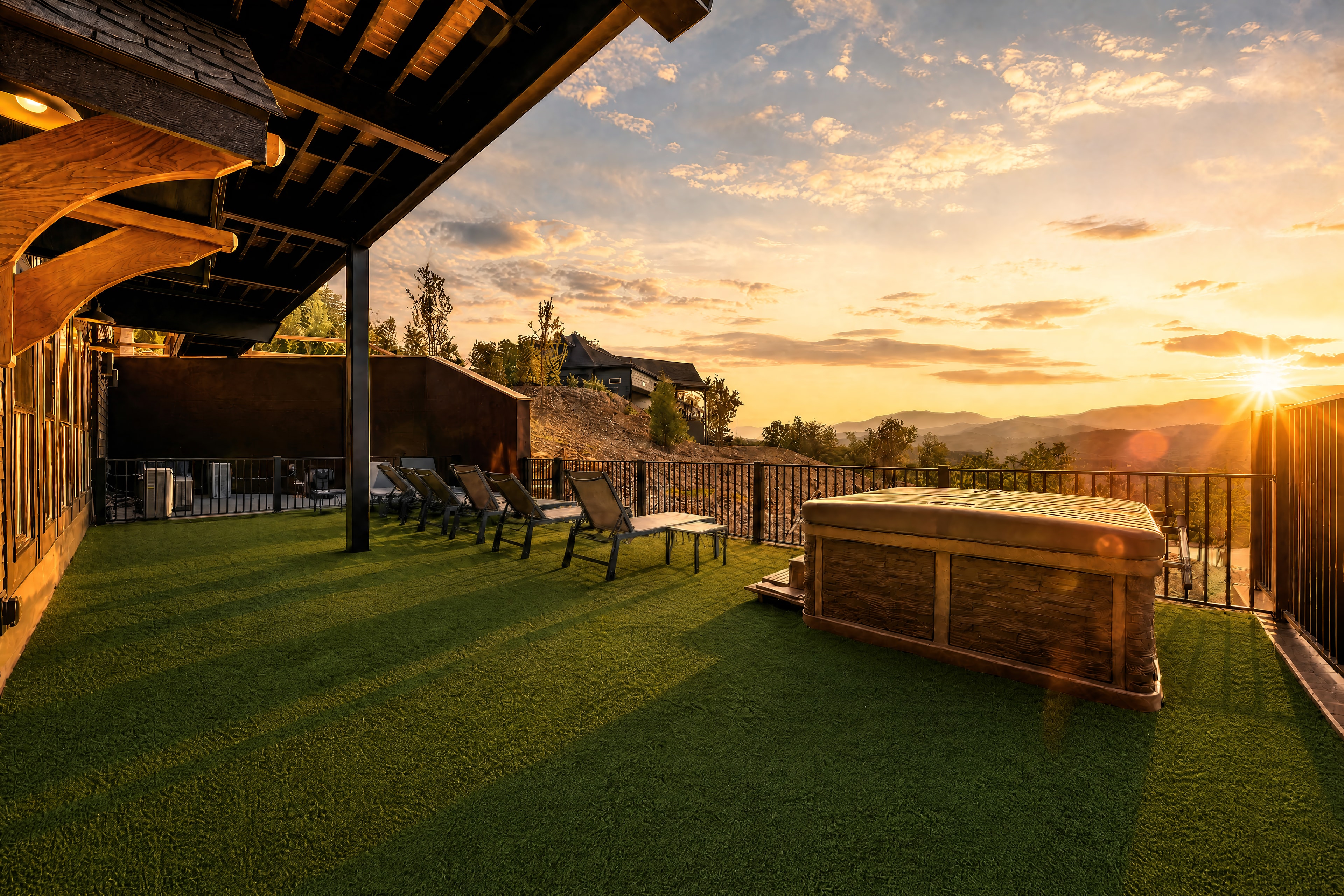 Wide patio view at Excalibur with covered hot tub, lounge chairs, and sweeping Smoky Mountain sunset panorama