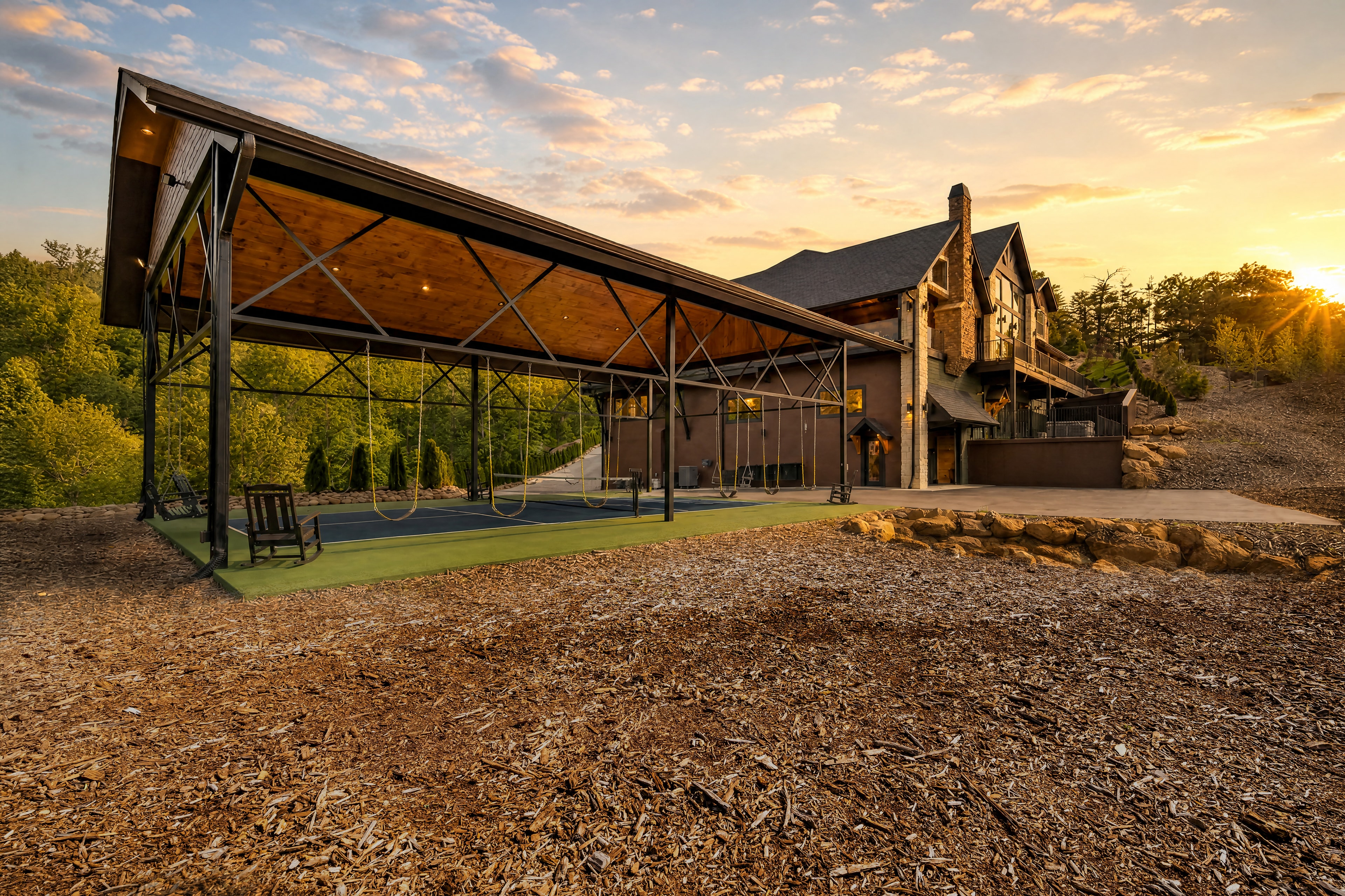 Exterior wide shot of Excalibur's covered pickleball court structure with the lodge and mountain sunset behind