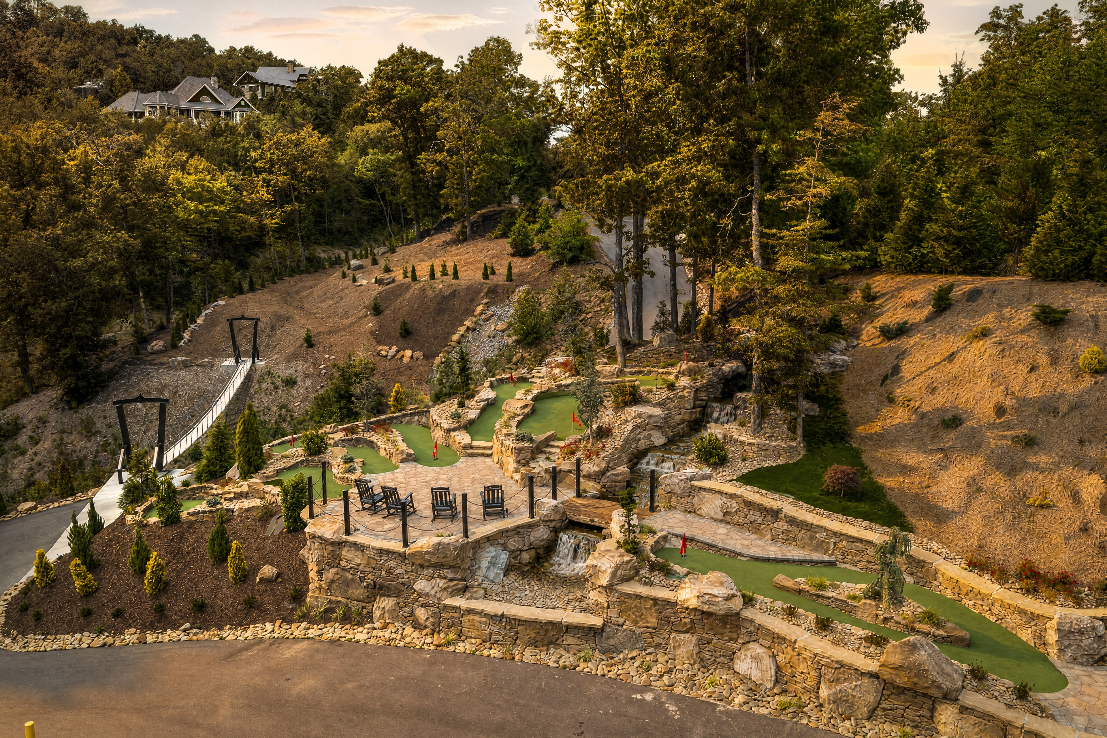Aerial view of Excalibur's private 9-hole putt-putt course carved into the Smoky Mountain hillside with stone walls and waterfall features
