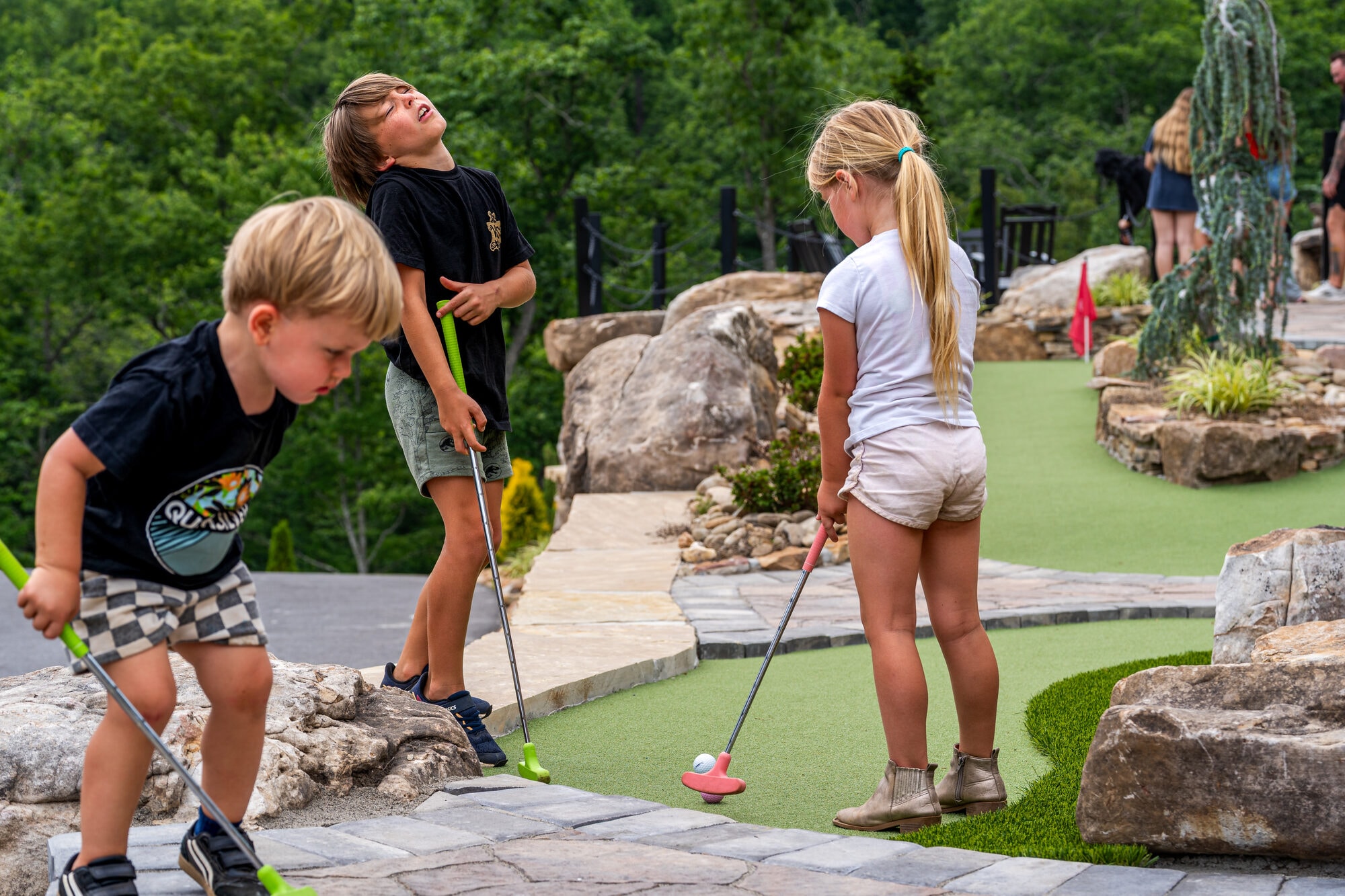 Children playing putt-putt golf at Excalibur Lodge natural stone course