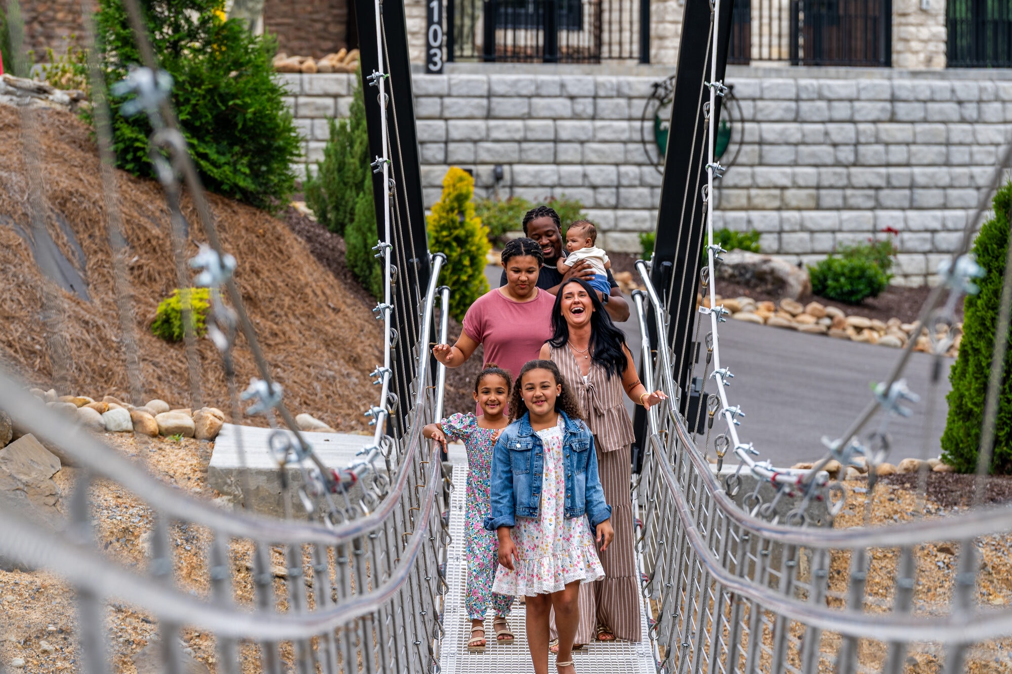 Family laughing together while crossing the 100-foot swinging bridge at Excalibur lodge