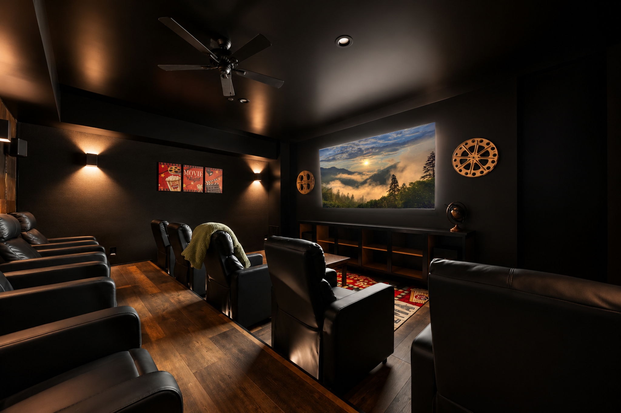 Front-facing view of Excalibur theater room with Movie Night posters, full rows of leather recliners, and projection screen