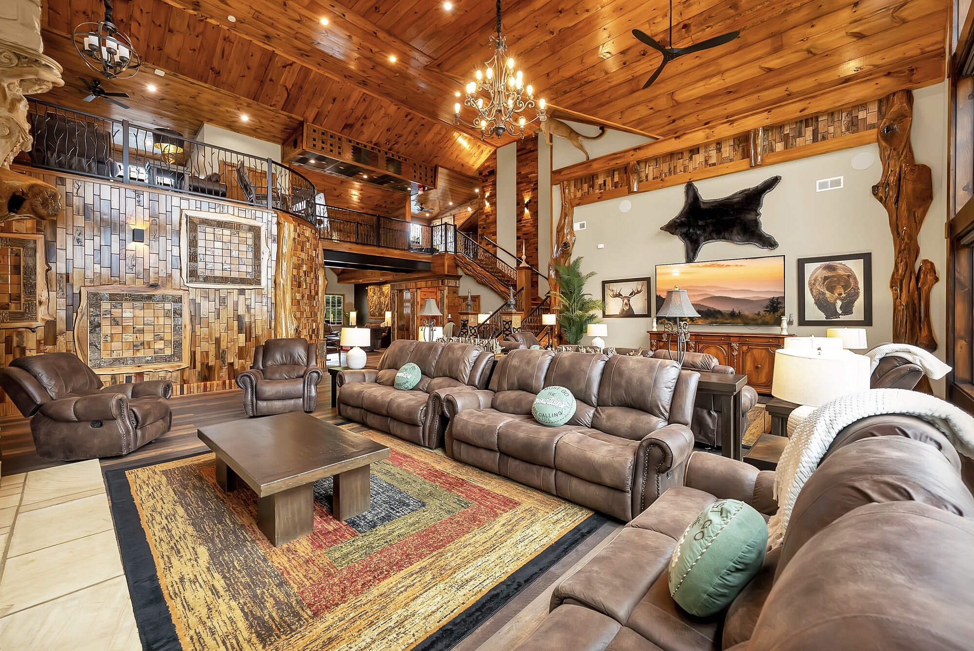 Excalibur great room with leather seating, stone fireplace, and soaring knotty pine cathedral ceiling